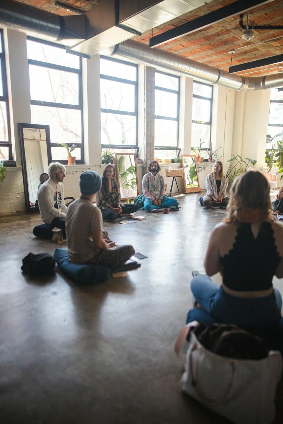Young adults in a circle discussing ideas on a concrete floor.