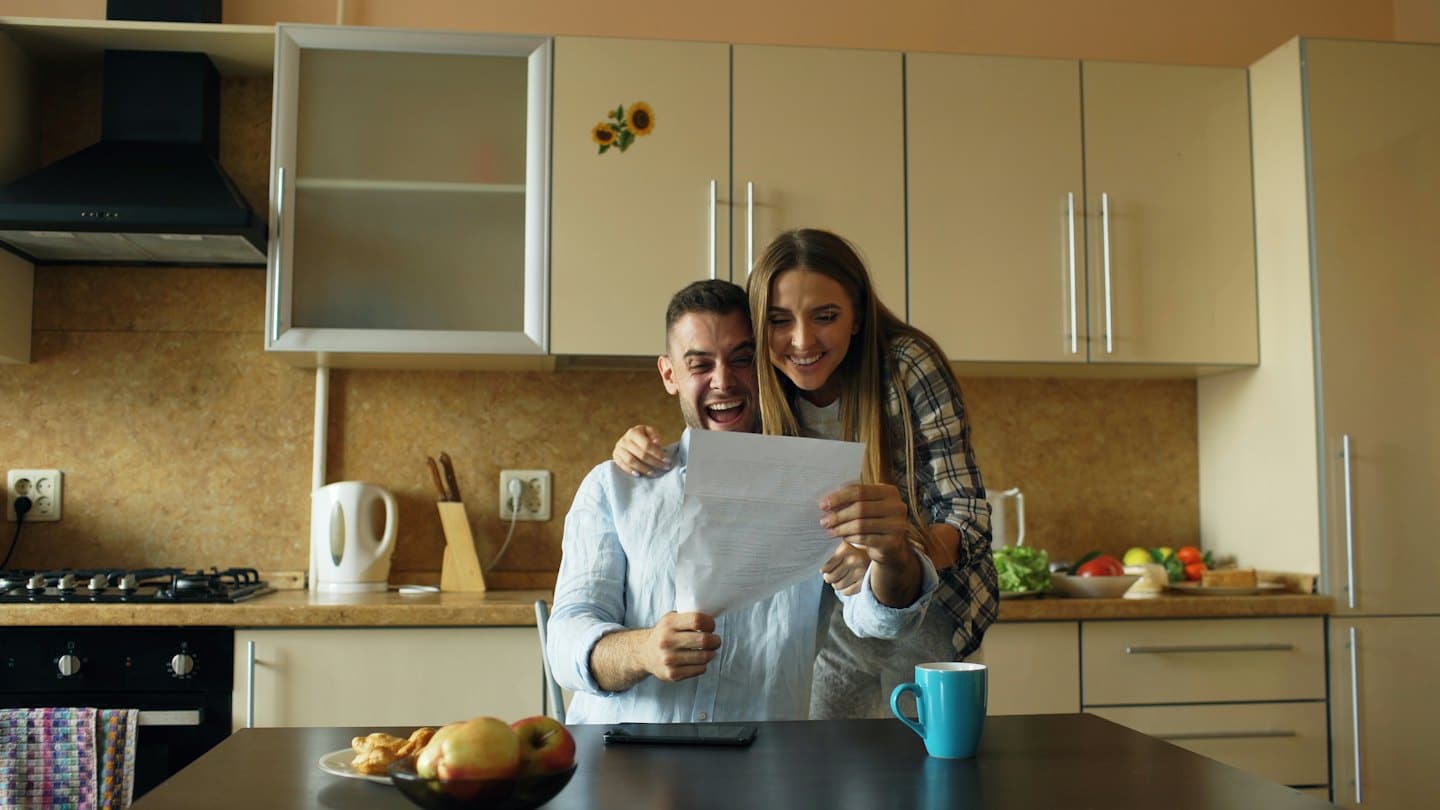 Couple reviewing document together at kitchen table with pastries.
